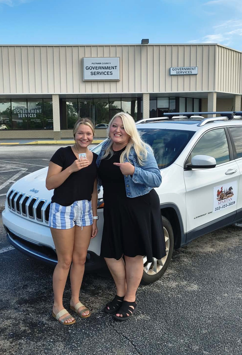 New driver celebrating passing the road test with her Spartan instructor